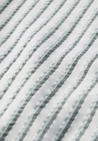 Tessuto di cotone con strisce sottili alternate in azzurro chiaro e grigio scuro, caratterizzato da un motivo testurizzato e una leggera lucentezza, che crea un effetto a strati.