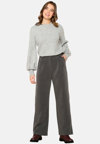 Light gray knitted sweater with puff sleeves, paired with high-waisted, wide-leg dark gray pants and burgundy lace-up boots.