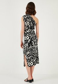 Black and white one-shoulder dress with a cinched waist, geometric and organic patterns, side slit, and soft fabric.