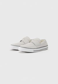 Lys grå slip-on sko laget av glatt stoff med rund tå og elastisk bånd. Har en hvit gummisåle med svarte striper.