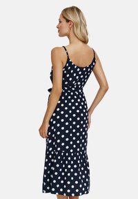 Nawigacyjna niebieska sukienka w białe kropki, z rozkloszowanym dołem, regulowanymi ramiączkami i paskiem w talii. Gładki materiał o luźnym kroju.