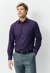 Fioletowa koszula z długim rękawem i zapięciem na guziki, o gładkiej fakturze i dopasowanym kroju, zestawiona z szarymi spodniami o teksturze oraz czarnym pasem.