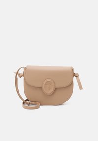 Světlé béžové kožené crossbody taška s zaobleným klopě, kulatým logem a nastavitelným popruhem. Hladký povrch, minimalistický design.