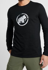 Czarny t-shirt z długim rękawem z teksturowanym, srebrnym logo mamuta w okrągłym wzorze z przodu.