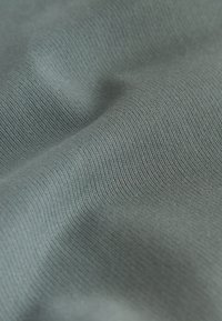 Gros plan d'un tissu côtelé doux gris clair montrant la texture et des plis légers.