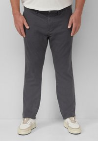 Dunkelgraue Baumwollhose mit geradem Schnitt, Gürtelschlaufen und Fronttaschen, kombiniert mit beigen Sneakers mit strukturiertem Obermaterial.