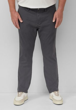 Dunkelgraue Baumwollhose mit geradem Schnitt, Gürtelschlaufen und Fronttaschen, kombiniert mit beigen Sneakers mit strukturiertem Obermaterial.
