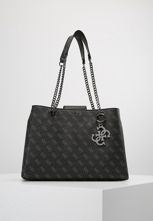 Black designer tote bag with chain handles, all-over logo pattern, and metal logo charm, placed on a white pedestal against a plain background.