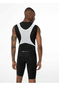 Schwarze Radsportträgerhosen mit einem weißen Netzoberteil. Sie verfügen über ein gepolstertes Sitzpolster, elastische Beinöffnungen und das Logo "PROTEST CYCLING" auf der Rückseite.