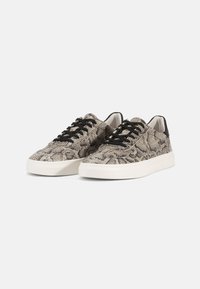 Sneakers featuring a snake print fabric in beige and black tones, black laces, and a white rubber sole. Flat, low-profile design.