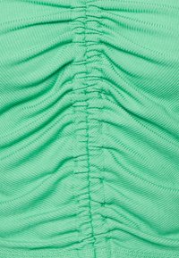 Tecido verde menta com textura pregueada, apresentando franzidos verticais ao longo do centro. Material suave e elástico com brilho sutil.