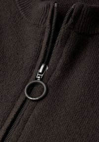 Černý pletený svetr s uzávěrem na zip se závěsným kroužkem, zobrazující texturovanou látku a vysoký límec.