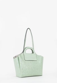 Grøn læder tote taske med blomsterperforering, struktureret form, enkelt top håndtag og justerbar skulderrem.