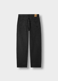 Sorte denimjeans med to baklommer og en brun lærmerke på linningen, vist flatt på en hvit bakgrunn.