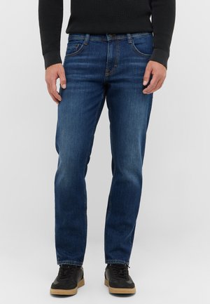 Jeans de denim azul con un corte recto, que cuentan con bolsillos frontales y un diseño clásico de cinco bolsillos. Combinados con zapatillas deportivas negras.