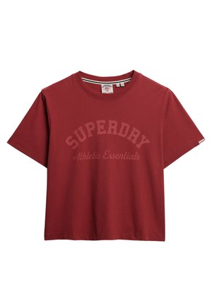 Camiseta de algodón roja con mangas cortas, cuello redondo y un gráfico de texto curvado que dice "SUPERDRY Athletic Essentials" en un tono más claro.