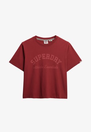 Camiseta de algodón roja con mangas cortas, cuello redondo y un gráfico de texto curvado que dice "SUPERDRY Athletic Essentials" en un tono más claro.