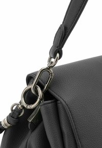 Borsa a tracolla in pelle nera con superficie testurizzata, dotata di un gancio a scatto in metallo e dettagli della tracolla in pelle, che enfatizza il suo design funzionale.