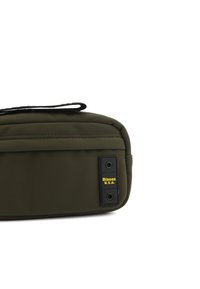 Borsa oliva in materiale sintetico, con superficie testurizzata, due inserti circolari neri e un'etichetta logo gialla.