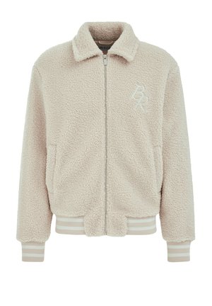 Gaučasta, bež skraćena bomber jakna izrađena od plišanog materijala; sadrži prednji zip, mekano kragnu i rebraste prugaste manžete i donji rub. Prisutan detalj s logotipom.