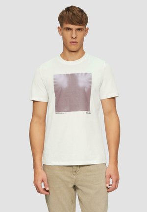 Witte katoenen t-shirt met een vierkant grafisch ontwerp in gedempte roze tinten. Korte mouwen, ronde hals en een relaxte pasvorm, gedragen met lichtbeige broek.