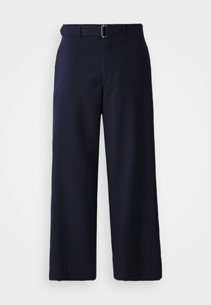 Pantalons large bleu marine en tissu texturé, dotés d'une ceinture avec une boucle en argent et d'une coupe droite, soulignée par des lignes épurées.