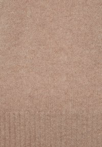 Helle braune Strickpullover-Stoff mit einer weichen, strukturierten Oberfläche. Rippdetail am unteren Saum. Gleichmäßige Farbe mit subtilen Variationen.