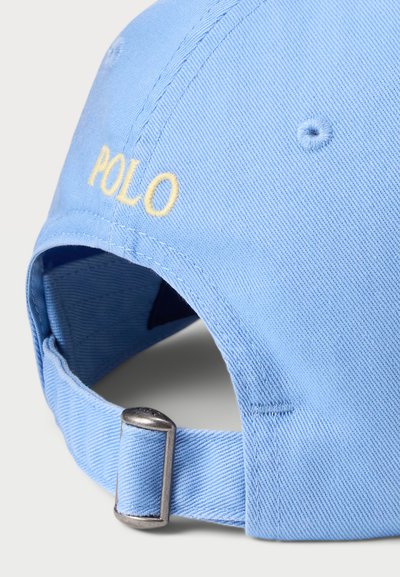 Világoskék pamutsapka ferde bordázott textúrával. Sárga "POLO" hímzéssel és fém csúszkás méretállítóval a hátsó részen.