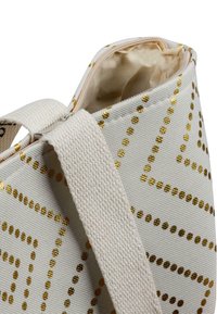 Beige-Canvas-Shopper mit goldenen Punkten, mit Reißverschluss und stabilen Stoffschlaufen. Das Innere ist mit einem hellen Stoff ausgekleidet.