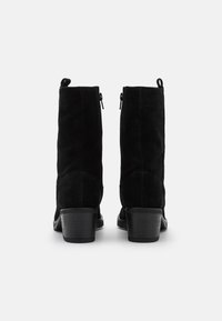 Svarta mocka ankelstövlar med klack, med en slät yta, bakfickor och dragflikar högst upp.