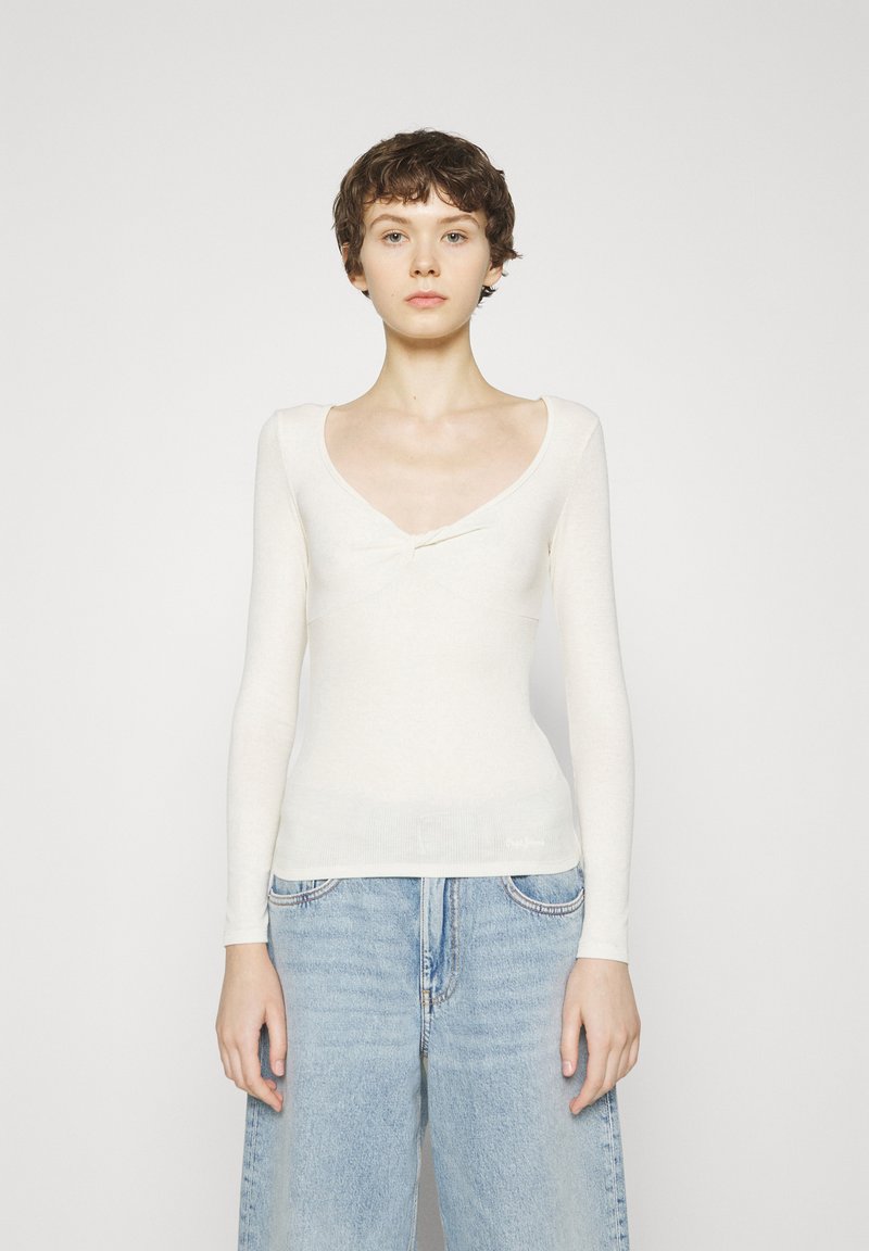 Maglia a maniche lunghe, attillata, in morbido tessuto color crema con scollo a barca e dettaglio a torsione sul petto. Maglia a trama con costine.