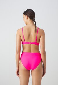 Conjunto de biquíni rosa brilhante com alças ajustáveis e calções de cintura alta. O material é liso, sem padrões ou detalhes de hardware visíveis.