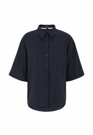 Tengerészkék gombos ing gallérral, rövid ujjakkal és bal oldali mellzsebbel. Az anyag sima, enyhén fényes megjelenésű.