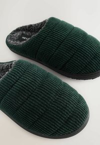 Pantofole in corda verde con una morbida fodera interna grigia. Presentano un design trapuntato e una suola in gomma nera durevole.