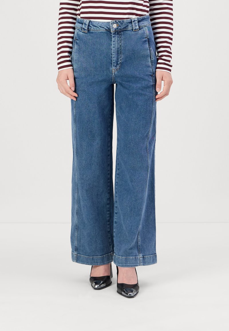 Jeans de mezclilla azul de pierna ancha con cintura alta, con cierre de botón, presillas para cinturón y bolsillo estándar. Acabado limpio en el dobladillo.