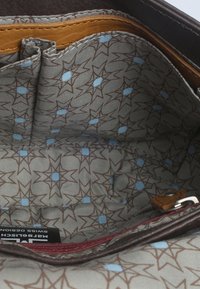 Busta interna in pelle marrone con bordo in pelle beige; foderata con un tessuto a motivi che presenta diamanti blu chiaro e stelle marroni.