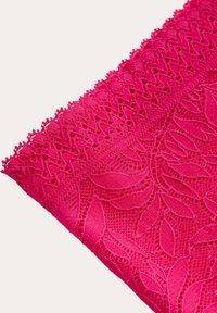 Fuchsia spets tyg med intrikata bladmönster och strukturerad detalj. Övre kanten har en vågig trim för extra dekoration.