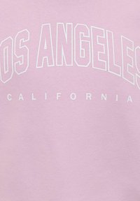 Tissu rose clair avec des lettres blanches en bloc formant le mot « LOS ANGELES » en arc au-dessus de lettres plus petites formant « CALIFORNIA » en ligne droite.