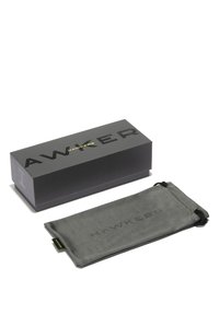 Harmaa suorakaiteenmuotoinen aurinkolasikotelo mustalla kiristysnyörillä ja kohokuvioitu "HAWKERS"-logo. Mukana musta laatikko, jossa paksulla fontilla teksti "HAWKERS".