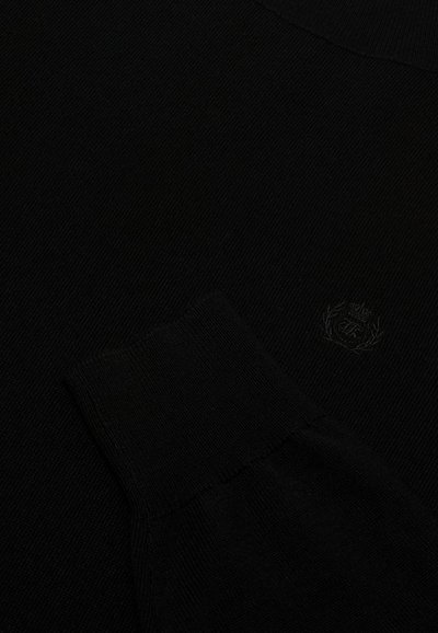 Suéter de punto negro con puños acanalados y un sutil bordado de logo. La textura parece suave y tiene un grosor medio.