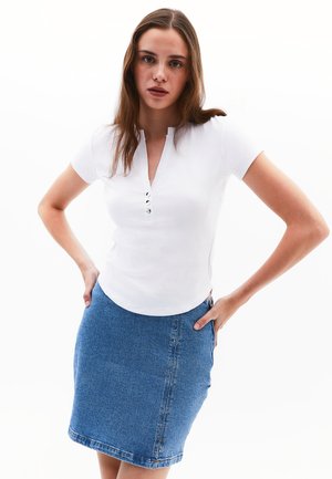Top bianco a coste con maniche corte e scollo a V, impreziosito da tre bottoni, abbinato a una gonna di jeans blu lunghezza ginocchio. Tessuto morbido, design informale.