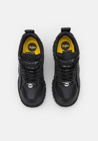 Black athletic shoes with a textured synthetic upper, yellow interior lining, and prominent logo. Features thick rubber sole and lacing system.