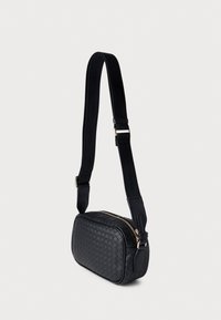 Czarna pleciona torba na ramię z zamkiem błyskawicznym, o prostokątnym kształcie, ze starannymi przeszyciami i regulowanym paskiem. Elementy ozdobne w kolorze złotym.