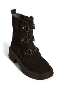 Brauner Wildleder-Stiefelette mit klobigem Absatz, verziert mit drei dekorativen Riemen mit silbernen Kettendetails und Metallknöpfen. Glattes Innenfutter.