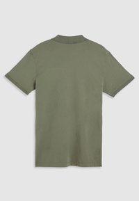 Polo vert olive à manches courtes, col plat, avec détails surpiqués aux extrémités des manches. Fabriqué en tissu de coton doux.