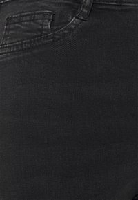 Jeans noirs en denim, avec une texture lisse, un design classique à cinq poches et un léger éclat sur le tissu.