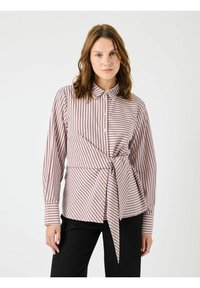 Gestreepte blouse in lichtroze en donkerroze met een kraag, een gebogen onderkant en een detail met een strik aan de voorkant. Lange mouwen met knoopmanchetten.