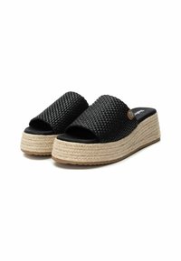 Sandalias de deslizamiento tejidas en negro con una correa ancha, suela de plataforma de yute y suela de goma. Presenta un pequeño acento metálico en la correa.