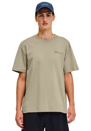 Khaki bomulds t-shirt med afslappet pasform, der har et lille trykt logo på venstre side, parret med en blå kasket.