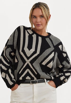 Maglione lavorato a maglia bianco e nero con motivi geometrici, maniche lunghe, vestibilità comoda e scollatura rotonda, abbinato a pantaloni color crema.